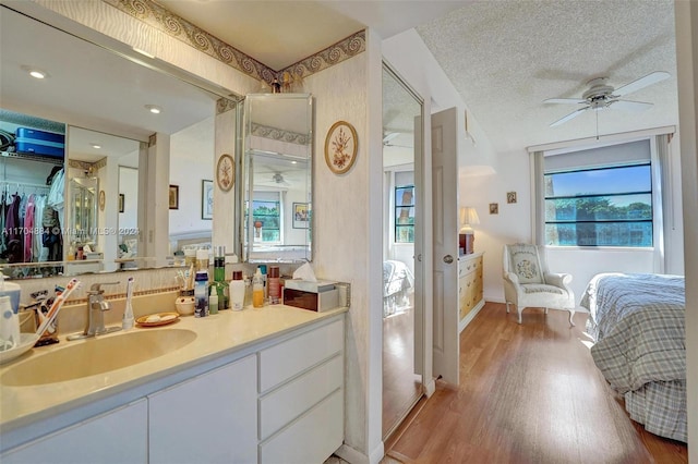 bathroom with hardwood / wood-style flooring, ceiling fan, a textured ceiling, and vanity