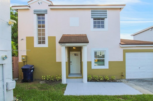 view of front of house featuring a shingled roof, an attached garage, and stucco siding