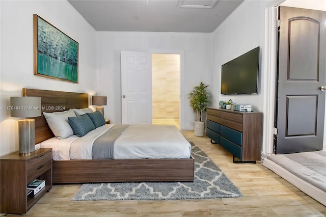 bedroom with light wood-style floors and connected bathroom