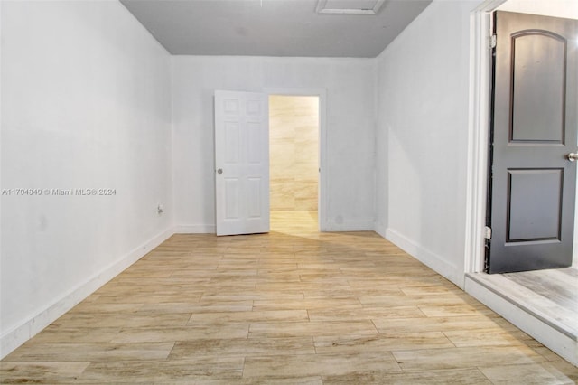 unfurnished bedroom featuring ensuite bath, light wood-style flooring, and baseboards