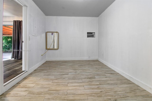 spare room featuring a wall mounted air conditioner and light wood finished floors