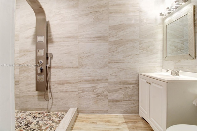 bathroom with tile walls, tiled shower, and vanity