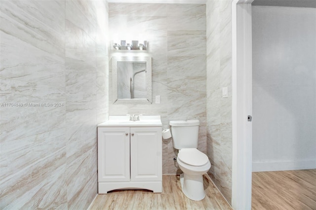 bathroom featuring vanity, wood finished floors, toilet, and tile walls