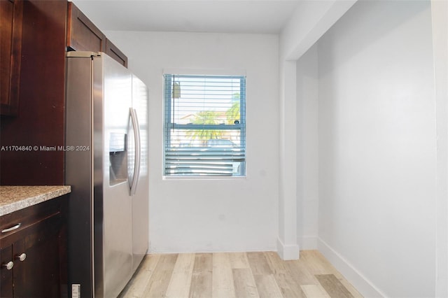 kitchen featuring baseboards, light countertops, dark brown cabinets, light wood-type flooring, and stainless steel fridge with ice dispenser