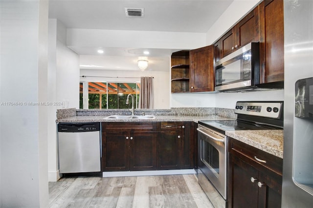 kitchen featuring dark brown cabinetry, visible vents, light wood-style flooring, appliances with stainless steel finishes, and a sink