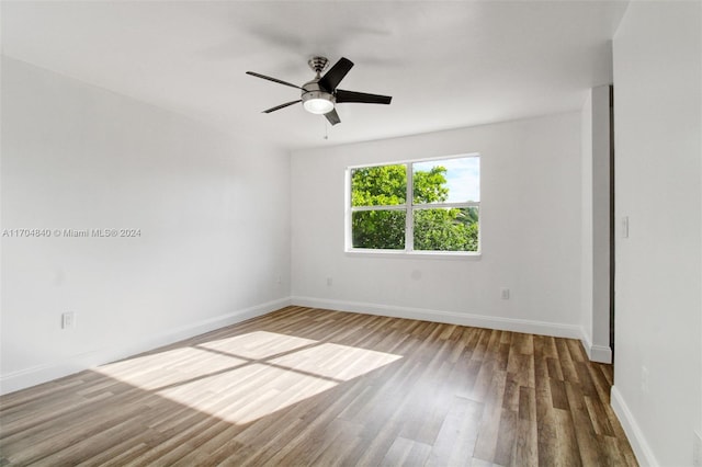 empty room with ceiling fan, wood finished floors, and baseboards