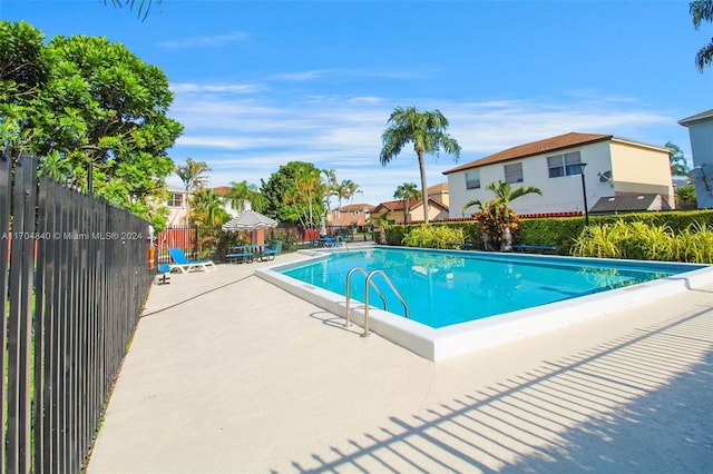 community pool with a patio area and fence