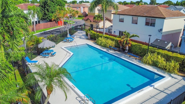 community pool featuring a patio area, fence, and a residential view