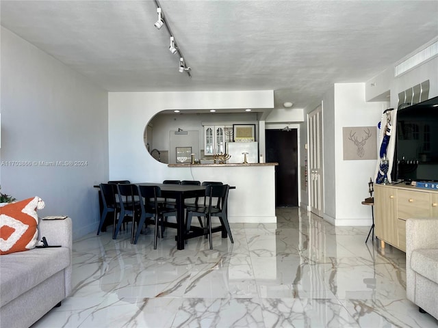 dining area with a textured ceiling and rail lighting