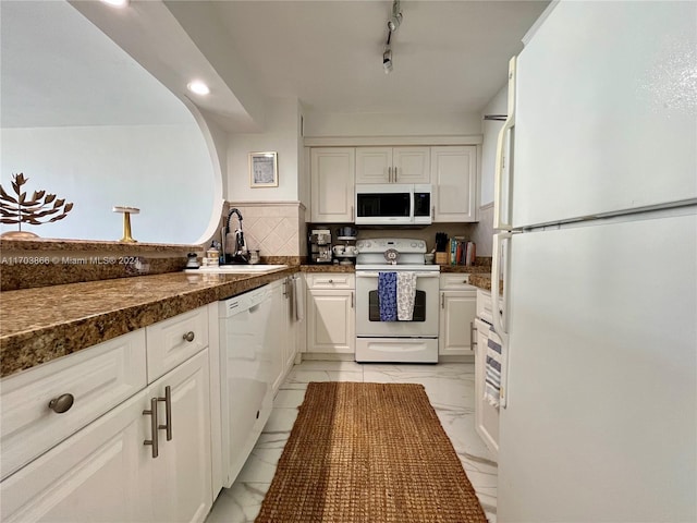 kitchen with decorative backsplash, rail lighting, white appliances, sink, and white cabinetry