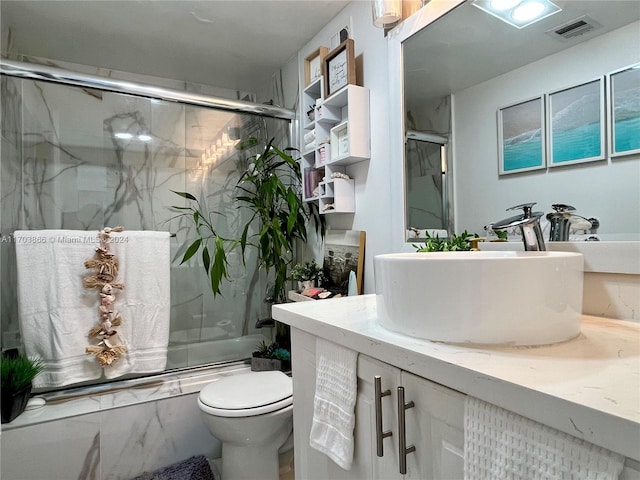 full bathroom with vanity, toilet, and bath / shower combo with glass door