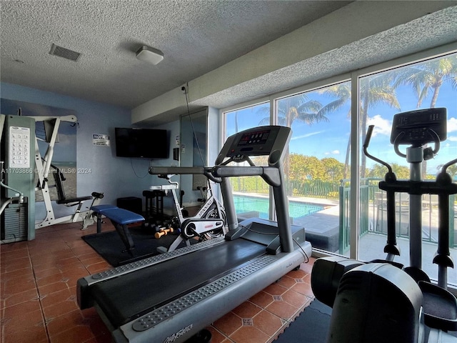 exercise area with dark tile patterned floors and a textured ceiling