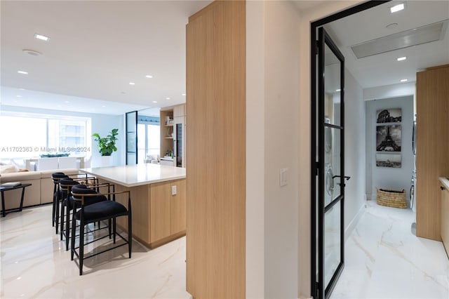 interior space with a kitchen breakfast bar, light brown cabinets, and a kitchen island