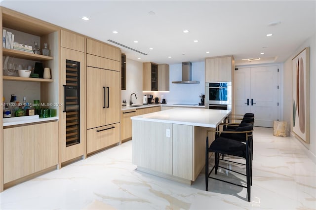 kitchen featuring a center island, light brown cabinets, black electric stovetop, wall chimney range hood, and a breakfast bar area