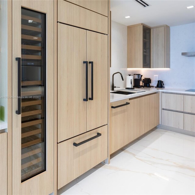 kitchen with light brown cabinets, black cooktop, beverage cooler, and sink