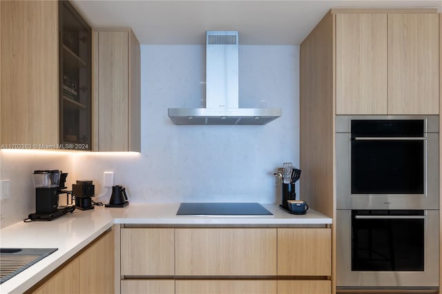 kitchen featuring light brown cabinetry, stainless steel double oven, wall chimney range hood, and black electric stovetop