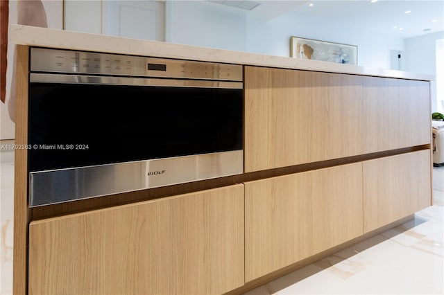 interior details with light brown cabinetry and oven