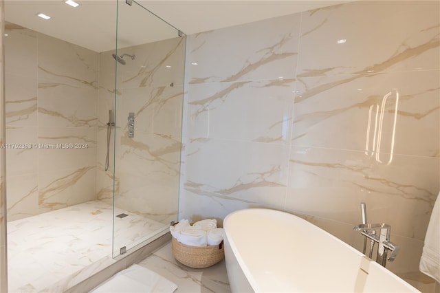 bathroom with tile walls and independent shower and bath