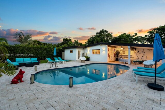 pool at dusk featuring a patio