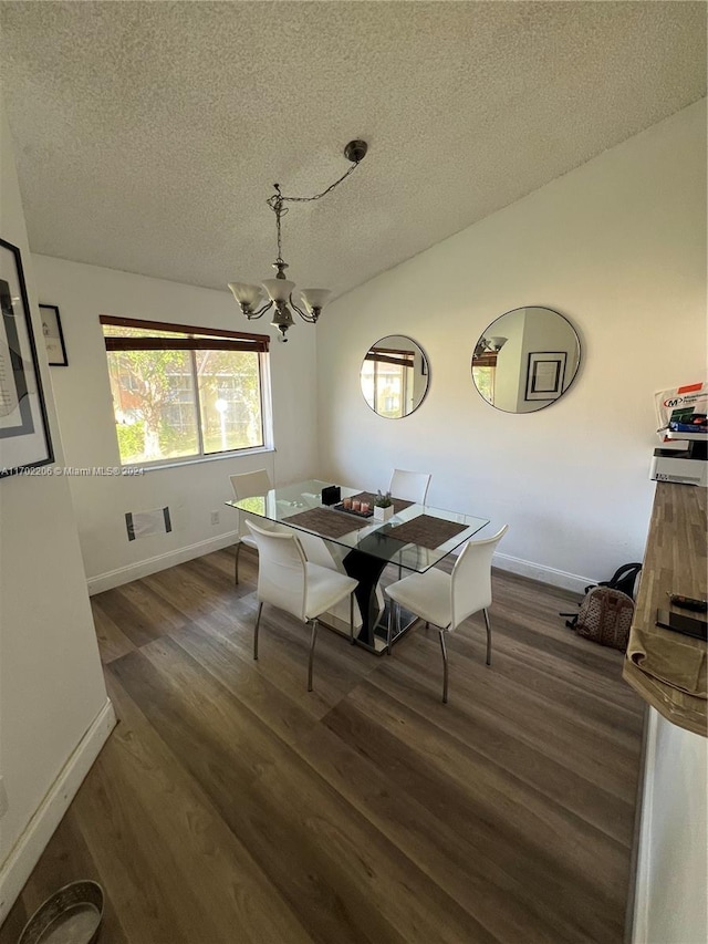 dining area featuring a textured ceiling, dark wood-type flooring, and a chandelier