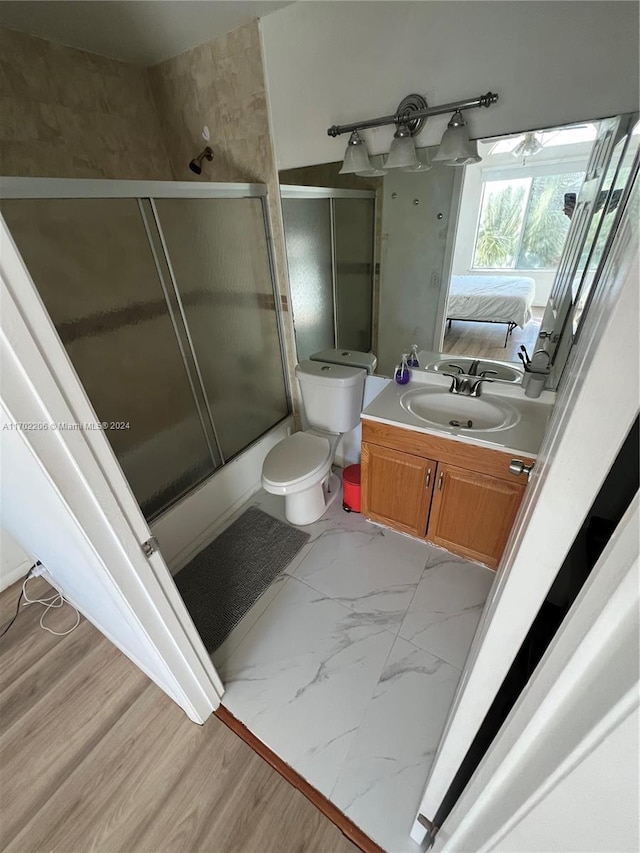 full bathroom with vanity, toilet, shower / bath combination with glass door, and wood-type flooring