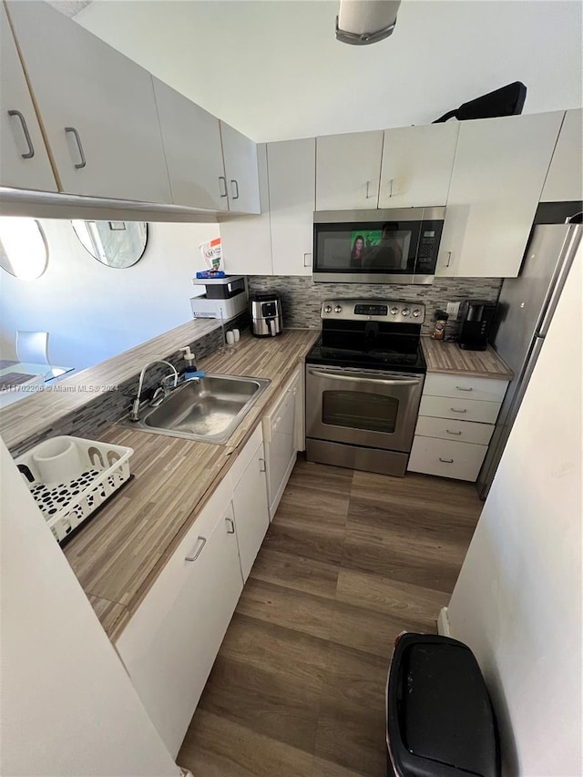 kitchen featuring white cabinetry, sink, dark wood-type flooring, stainless steel appliances, and decorative backsplash