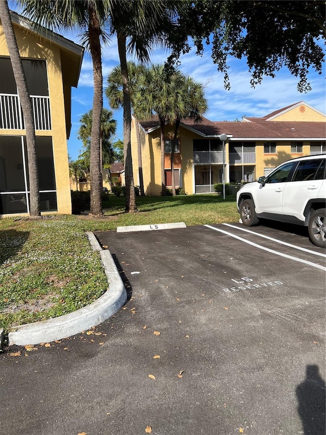 view of parking / parking lot featuring a lawn