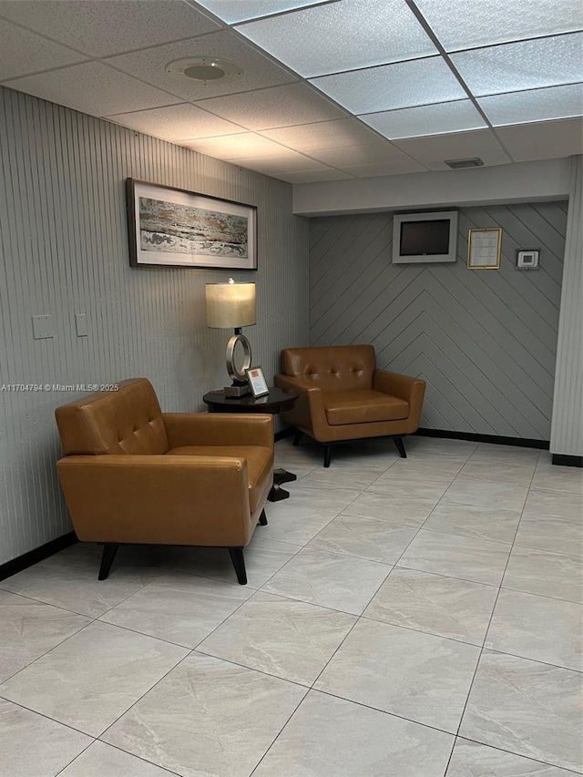 interior space featuring a drop ceiling and wood walls