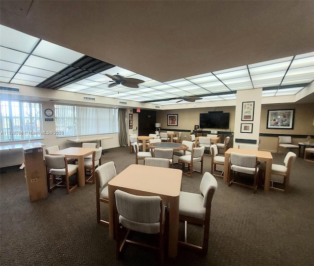 dining area featuring a paneled ceiling, dark carpet, and ceiling fan