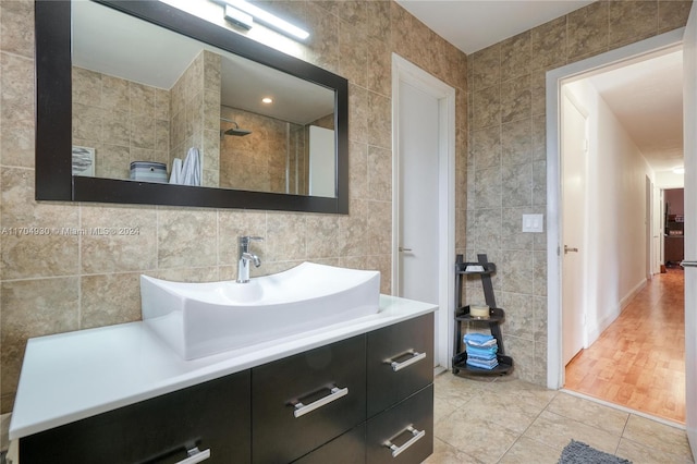 bathroom with walk in shower, vanity, hardwood / wood-style flooring, and tile walls