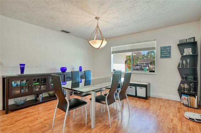 dining room with a textured ceiling and light hardwood / wood-style flooring