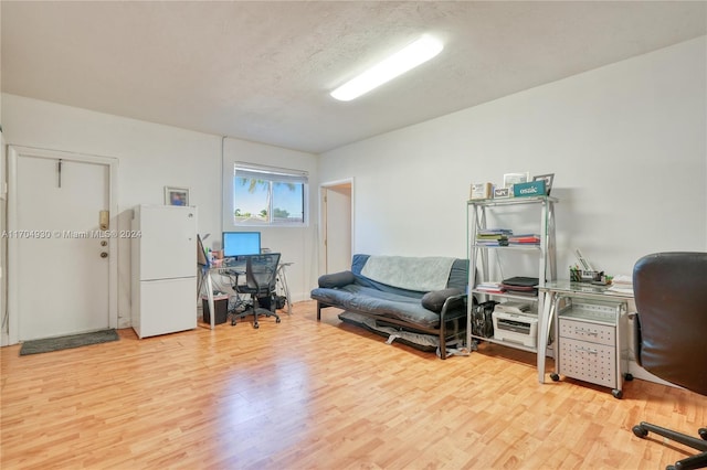 home office with light hardwood / wood-style floors and a textured ceiling