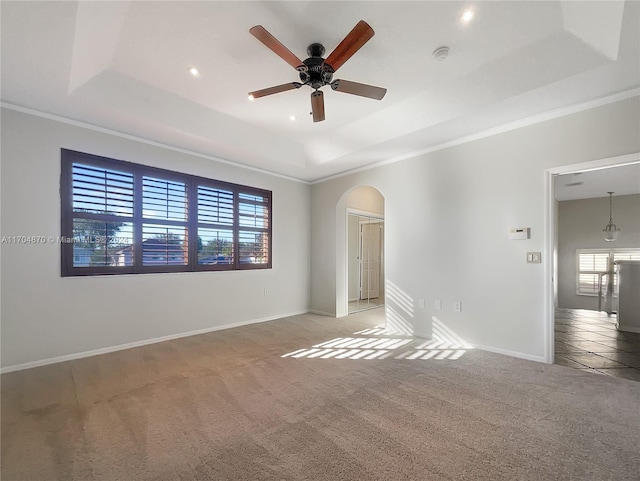 empty room featuring ceiling fan, light carpet, and a tray ceiling