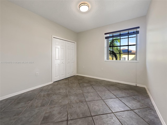 unfurnished bedroom with a textured ceiling and a closet