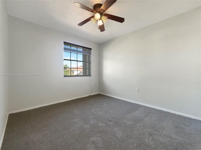 empty room featuring ceiling fan and dark colored carpet