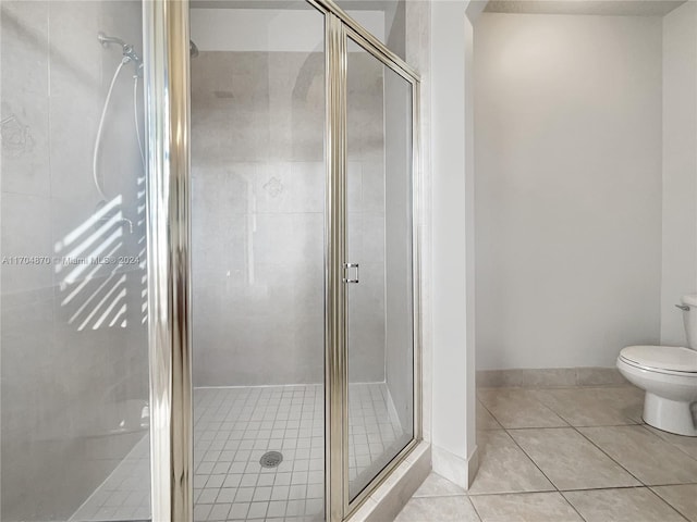 bathroom featuring tile patterned floors, toilet, and a shower with shower door