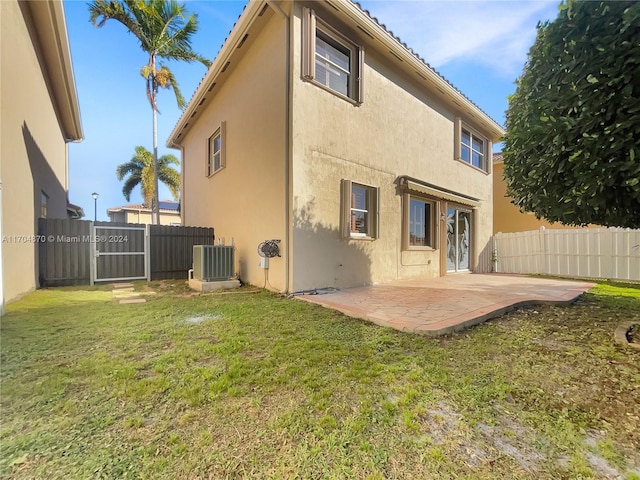 back of property with central AC unit, a patio area, and a lawn