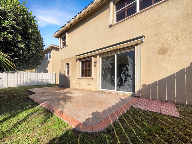 rear view of house with a patio and a lawn