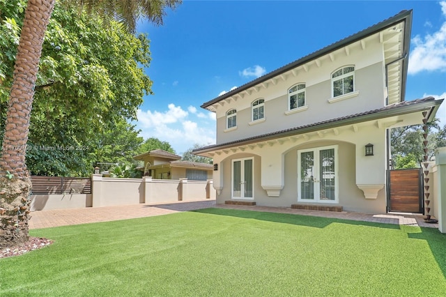 back of property with a yard and french doors