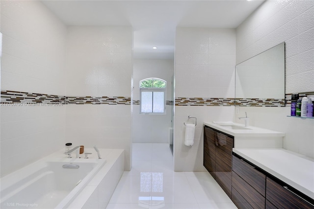 bathroom featuring tile patterned floors, tiled tub, vanity, and tile walls