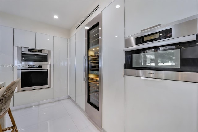 kitchen featuring light tile patterned flooring, white cabinets, and stainless steel double oven