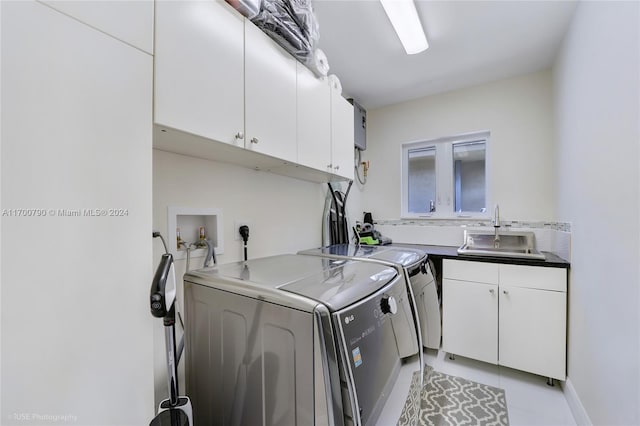 laundry area with cabinets, light tile patterned floors, washing machine and dryer, and sink