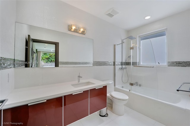 full bathroom featuring tile patterned floors, toilet, vanity, tile walls, and tiled shower / bath