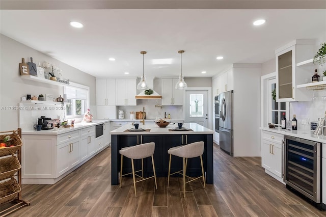 kitchen featuring custom exhaust hood, open shelves, beverage cooler, stainless steel fridge, and a kitchen bar