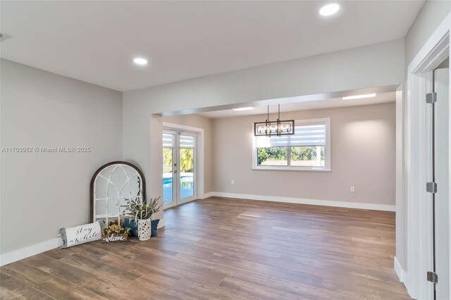 unfurnished room featuring hardwood / wood-style floors and a chandelier