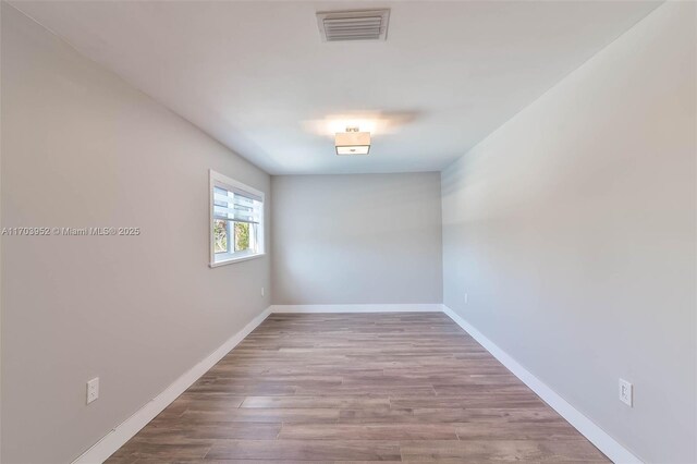 unfurnished room featuring visible vents, baseboards, and wood finished floors