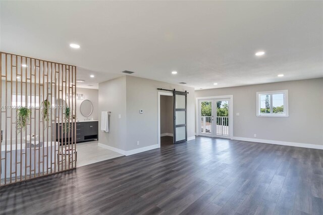 unfurnished room featuring french doors, dark hardwood / wood-style flooring, and a barn door