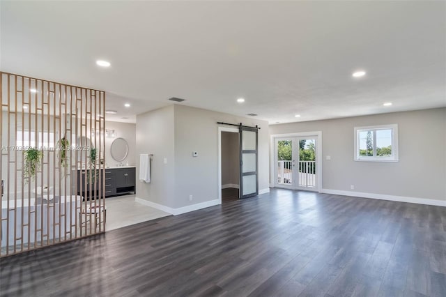 unfurnished room with wood finished floors, french doors, baseboards, and a barn door