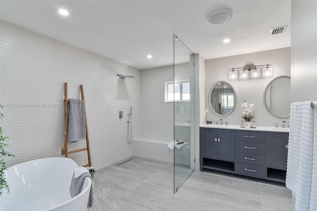 full bathroom featuring double vanity, visible vents, a freestanding bath, a sink, and walk in shower