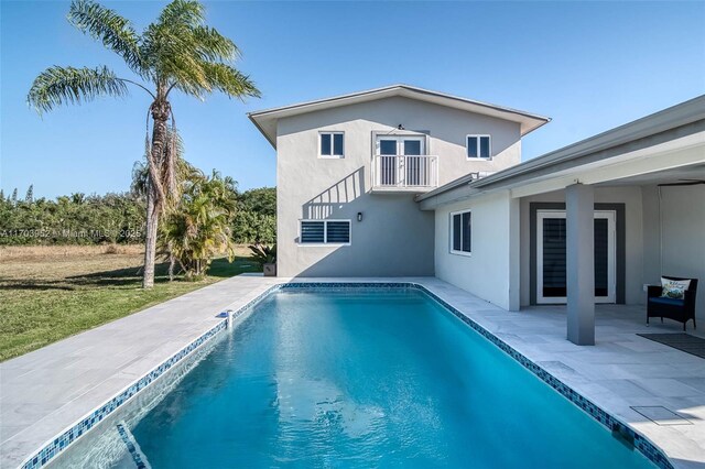 19450 SW 125th Ave, Miami, FL 33177 - rear view of house with a balcony, stucco siding, a patio, an outdoor pool, and a yard